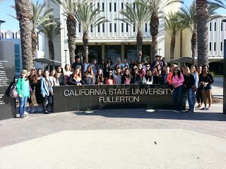 Students posing behind a California State University Fullerton Sign